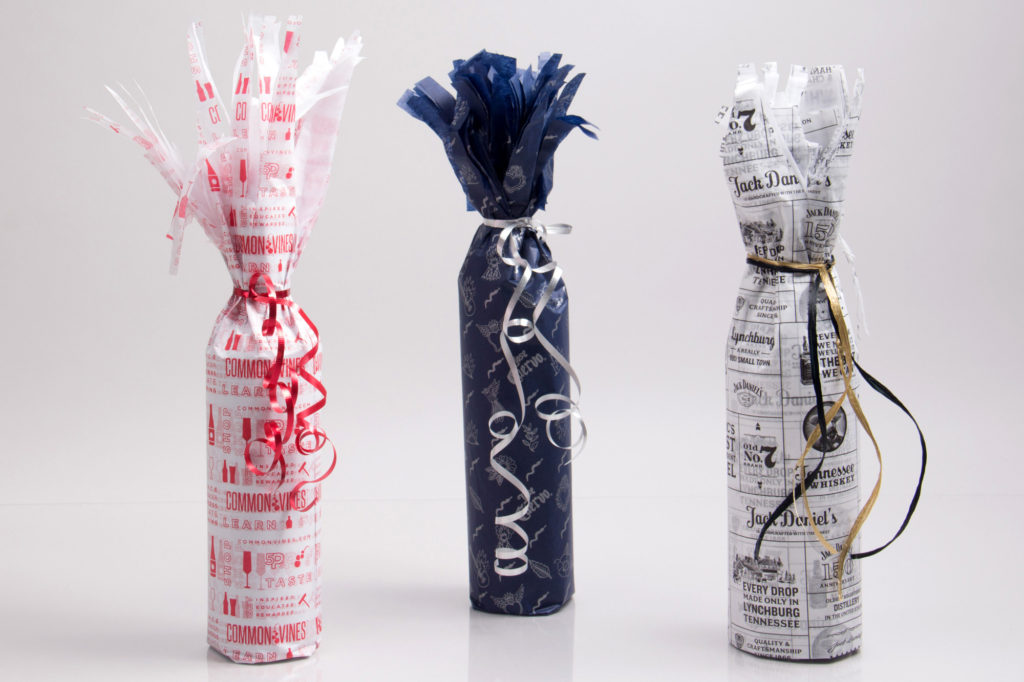 Wrapping bottles in tissue paper with ribbon ties
